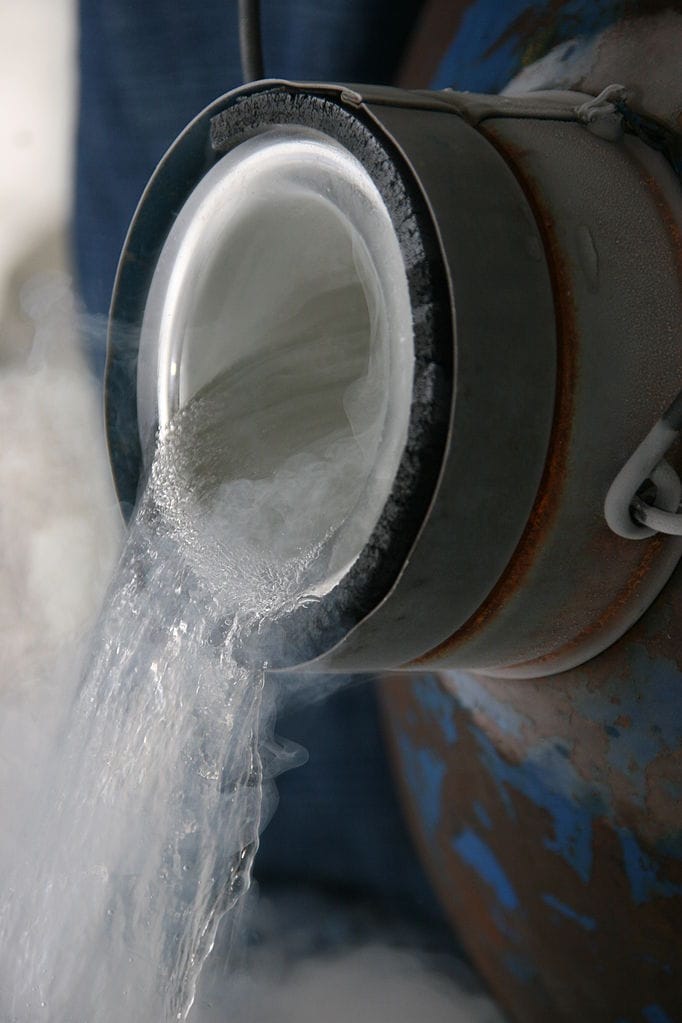A clear liquid being poured from an insulated container, producing vapor as it flows