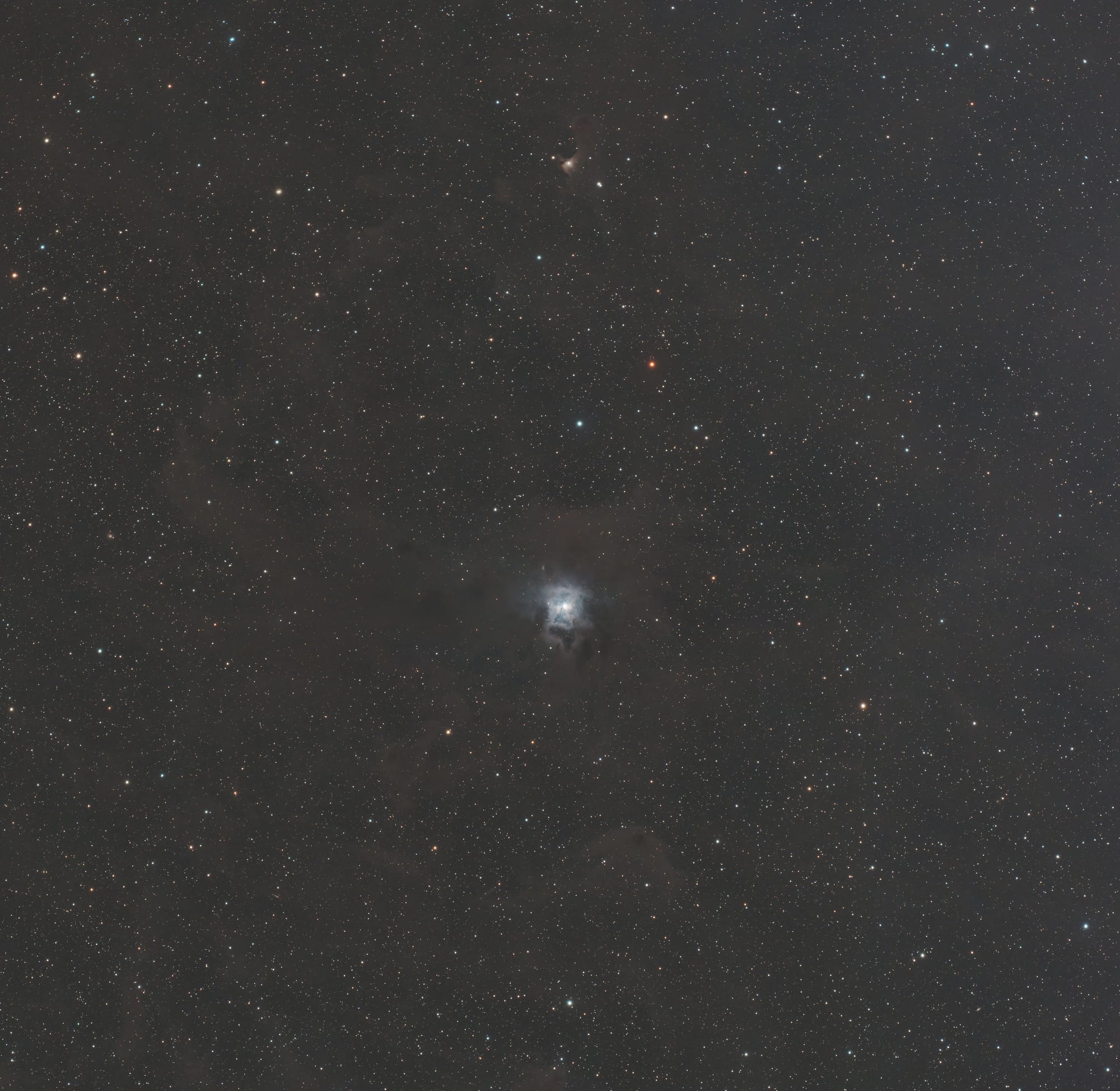 A round, blue nebula surrounded by gray clouds of dust