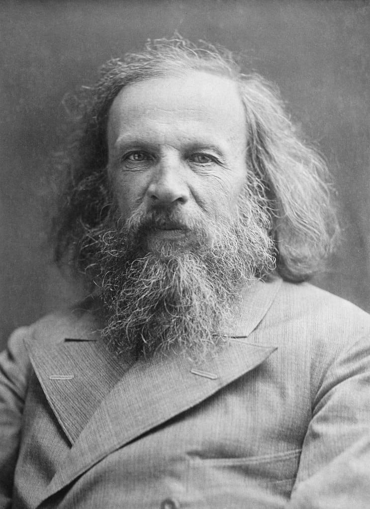 Black-and-white photograph of a man with long hair, a long beard, and wearing a suit