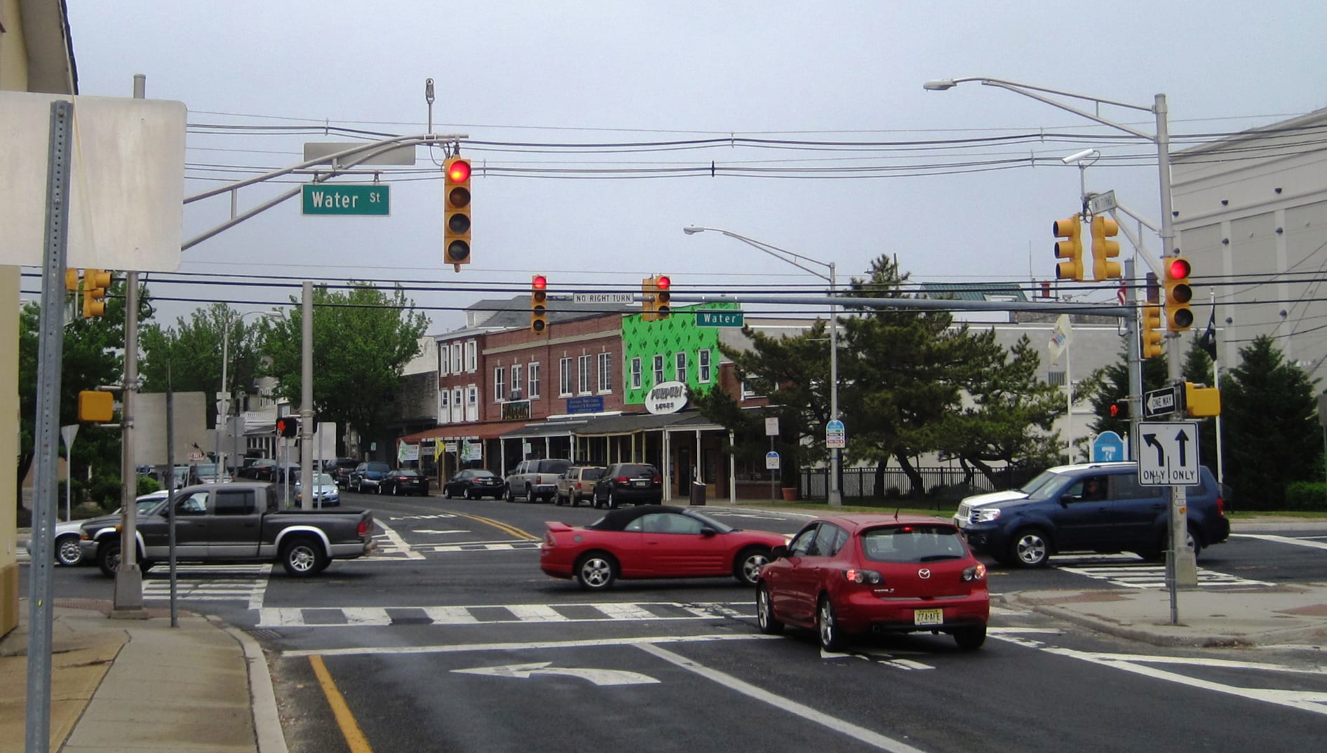 Photo of a downtown street, lined with shops and parked cars