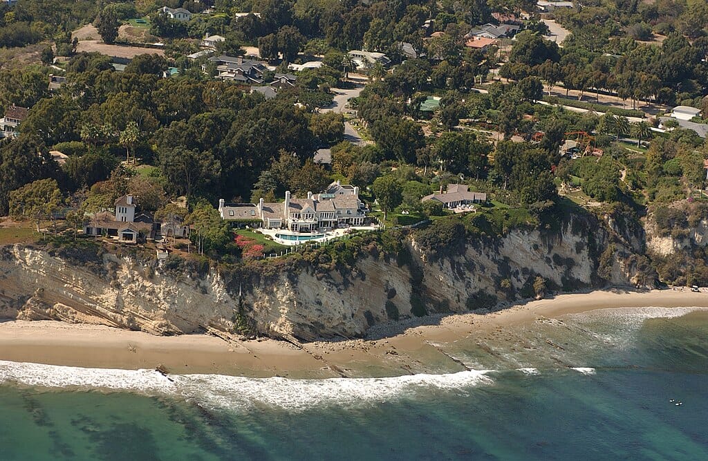 Aerial photograph of a mansion perched atop an oceanside cliff