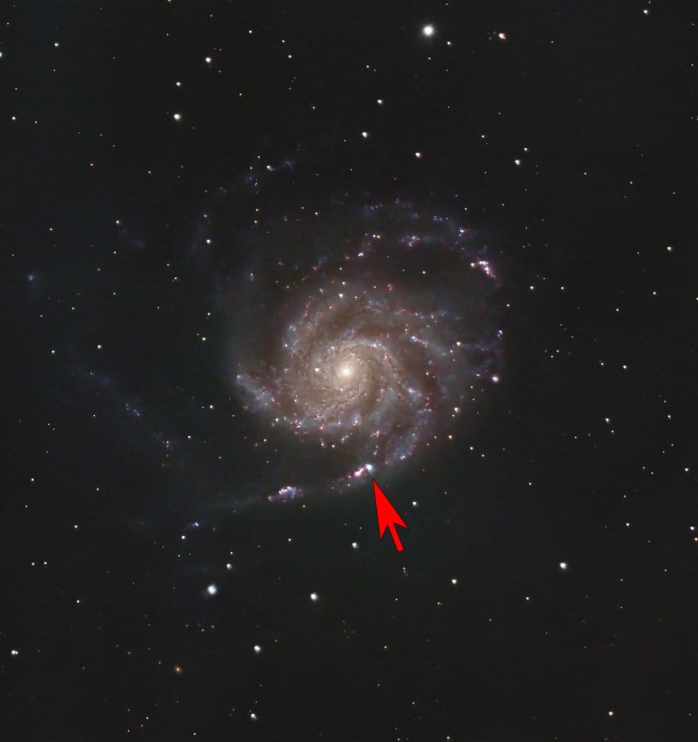 Photo of a spiral galaxy with an arrow superimposed that is pointing to a bright “star”