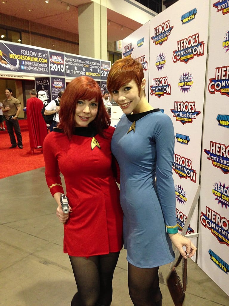 Photo of two women in Star Fleet uniforms from Star Trek: The Original Series; one is holding a phaser pistol