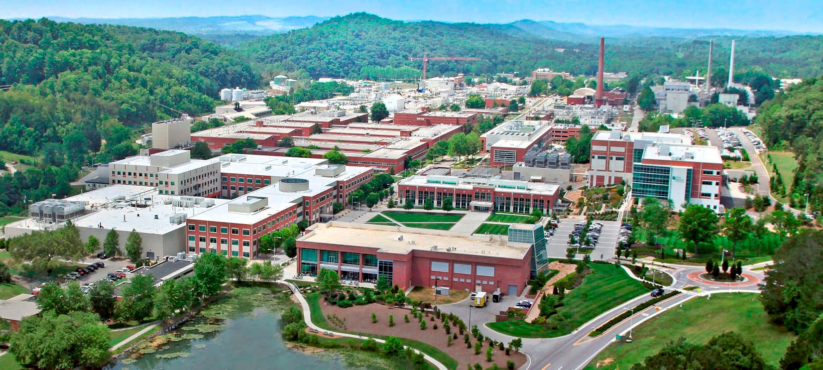 Aerial photo of a campus of office and industrial buildings nestled among tree-covered hills