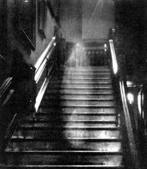 Black-and-white photo of a semi-transparent image of a woman on a staircase