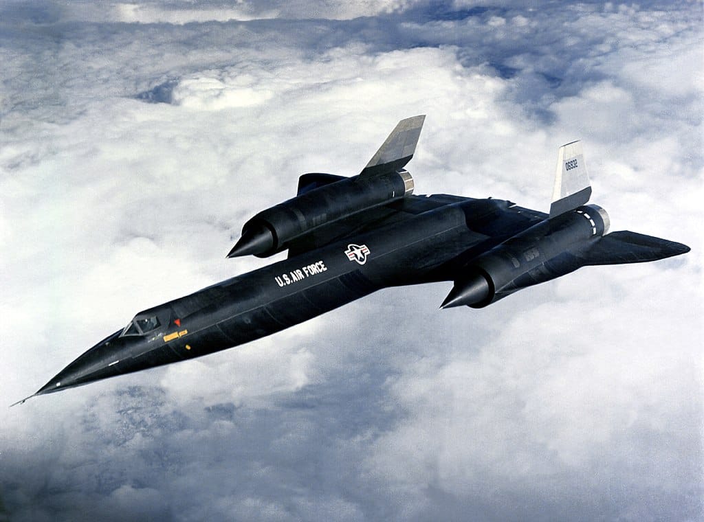 Photo of a black-colored, twin-engine US Air Force jet flying above clouds