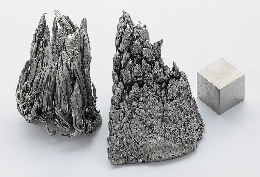 Photo of 3 samples of silvery metal, two having a tree-like structure and the third in the shape of a cube