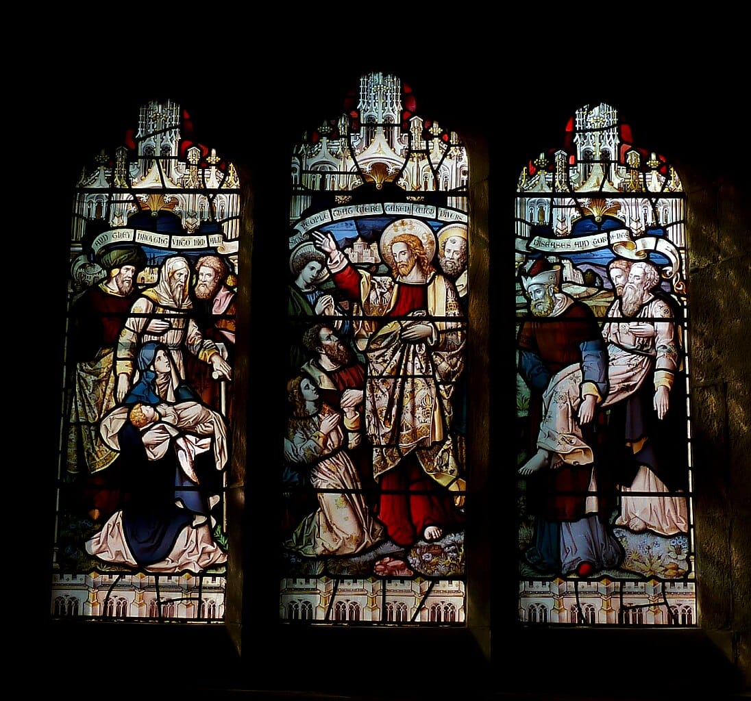 Photo of a triptych stained-glass window of Christ healing the sick and the text of Matthew 4:24