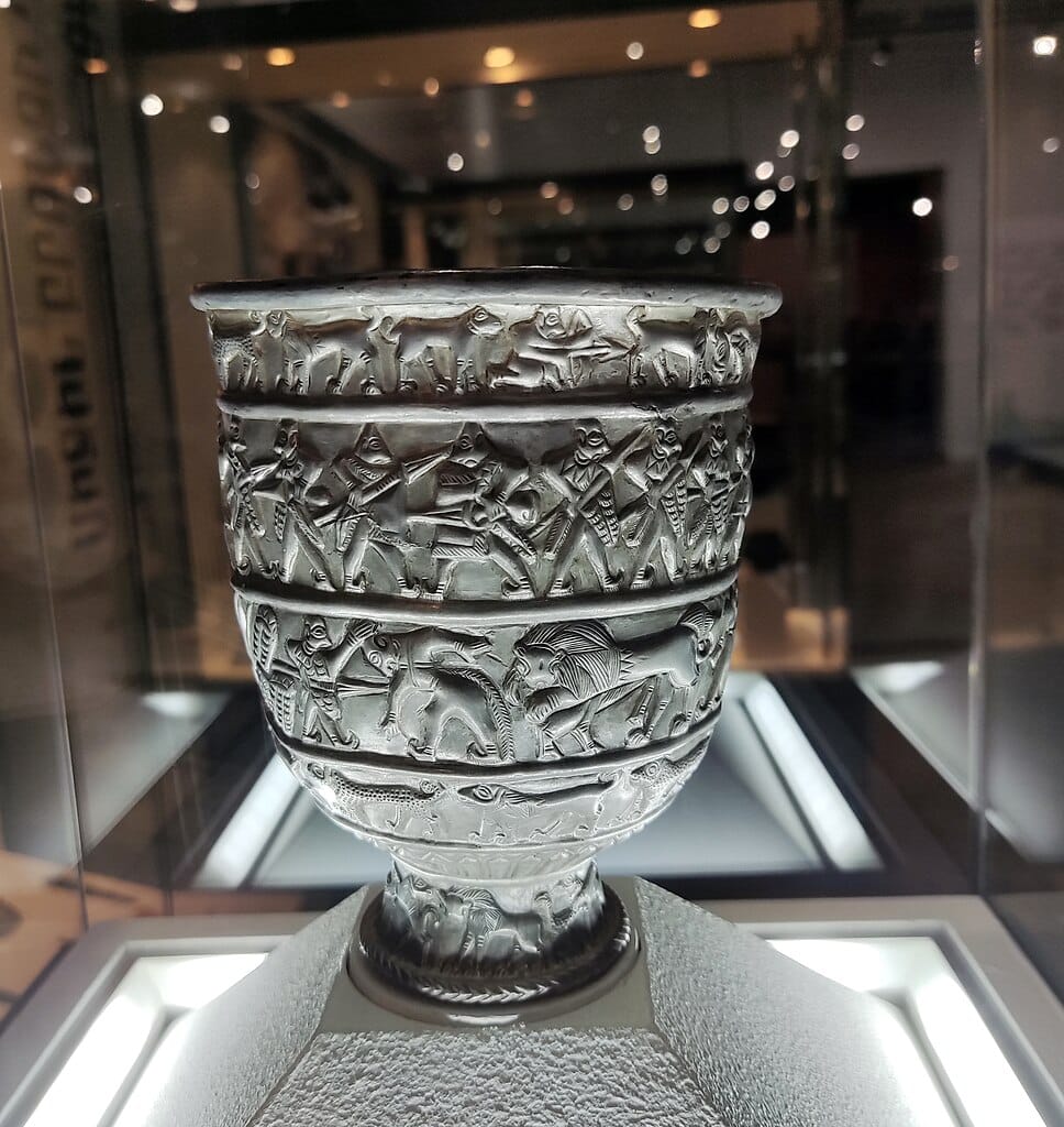 Photo of silver cup with images of warriors in battle and hunters killing animals on display in a museum