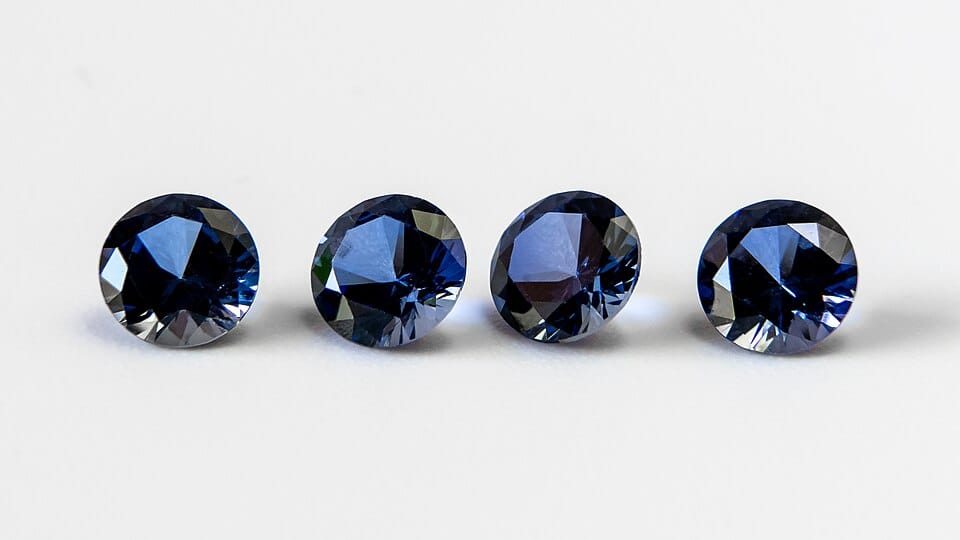 Photo of four, blue, faceted gemstones