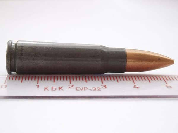 Photo of a rifle cartridge with the lead bullet encased in harder metal; a ruler shows the cartridge is about 5.5 cm long