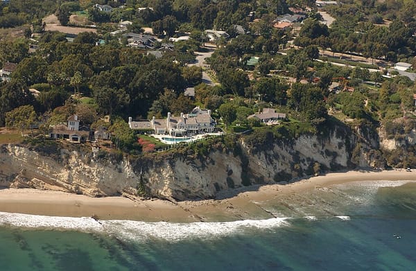 Aerial photograph of a mansion perched atop an oceanside cliff