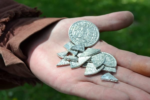 Photo of an open hand holding coins, one whole and others divided into segments