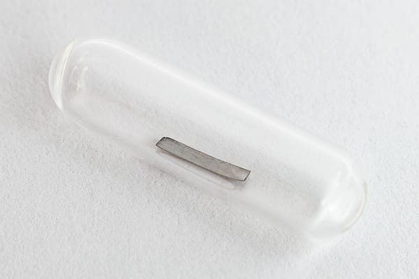 Photo of a strip of gray metal in a sealed glass tube