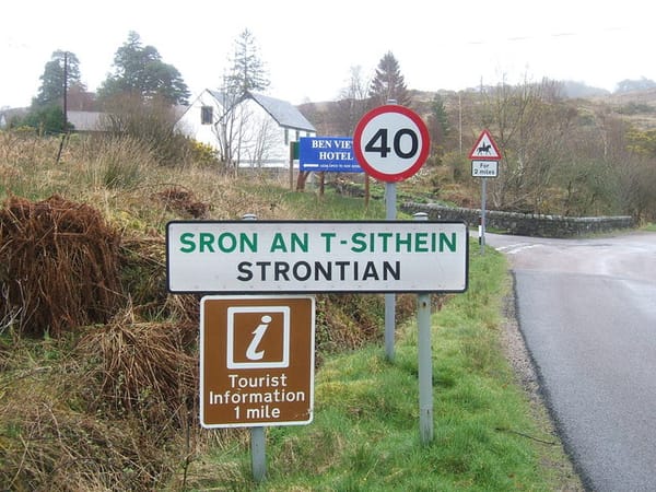 Photo of a roadside sign announcing drivers are entering the village of Strontian (Sron An T-Sithein), Scotland