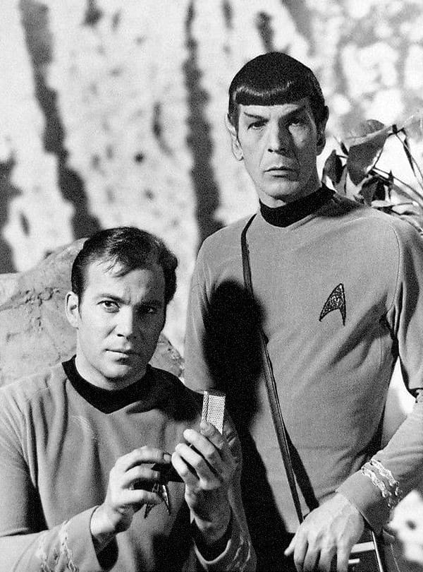 Black-and-white photo of William Shatner and Leonard Nimoy in Star Trek uniforms; Shatner is holding a communicator