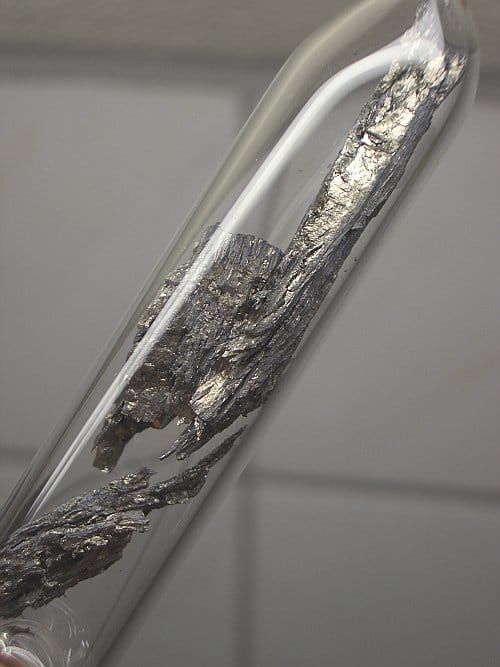 Photo of a jagged sample of a silvery metal in a glass ampoule