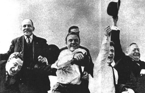 B&W photo of six men laugh and cheering and waving their hats in the air